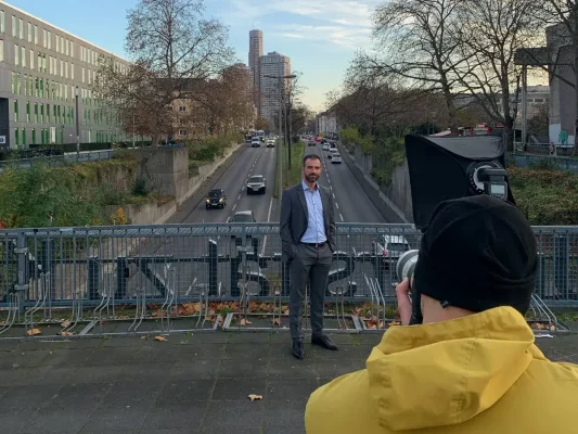 Making-of kreatives Outdoor-Businessshootings in Köln – Portraitaufnahme auf Uni-Brücke mit Stadtverkehr im Hintergrund, fotografiert von nonverbal | businessfotografie.