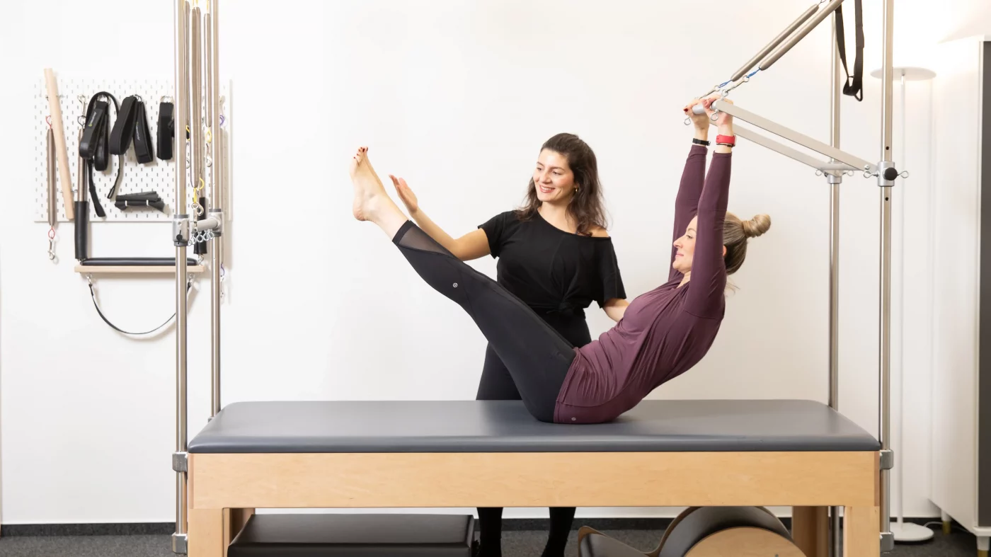 Valeria Perrelli begleitet eine Kundin bei einer Pilatesübung am Gerät im ORA Pilates Studio Köln – fotografiert von nonverbal | businessfotografie