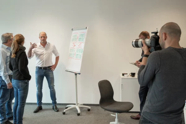 Businessfotografie in Köln – Joschi Alger beim Vortrag mit Team am Flipchart, fotografiert von nonverbal | businessfotografie.