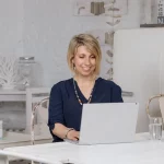 Angela Müller arbeitet lächelnd an einem Laptop – Businessfotoshooting in freundlicher Atmosphäre.