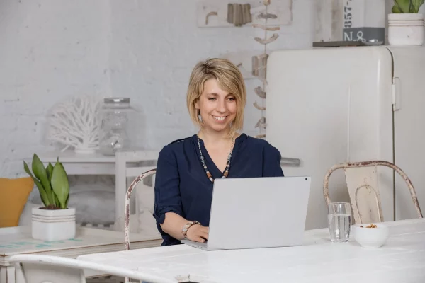 Angela Müller arbeitet lächelnd an einem Laptop – Businessfotoshooting in freundlicher Atmosphäre.